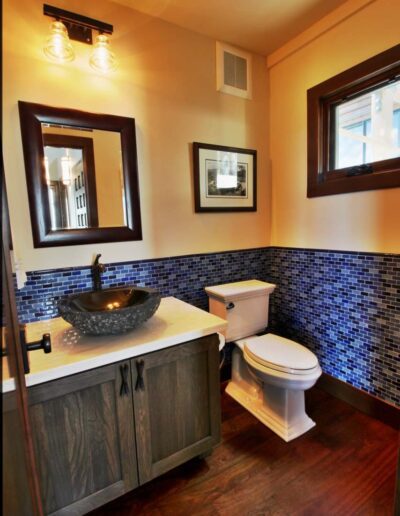 Modern bathroom with blue mosaic tile backsplash, vessel sink, and wooden vanity.