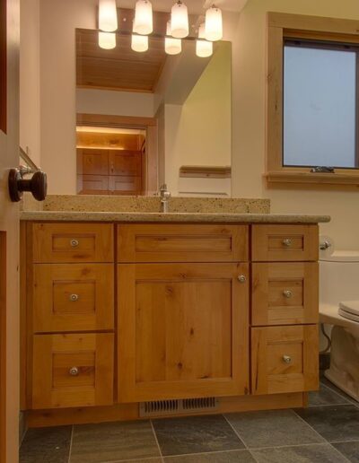 A warm-toned bathroom interior with wooden cabinetry and a granite countertop.