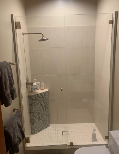 A modern walk-in shower with glass doors and neutral tile design.