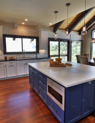 Spacious kitchen interior with white cabinets, hardwood floors, and a central blue island.