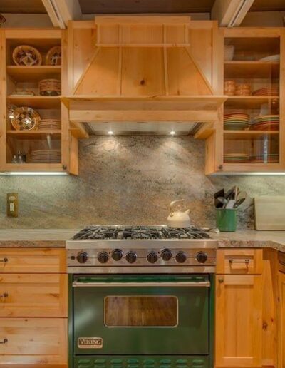 A kitchen featuring wooden cabinetry, a stone backsplash, and a green viking range stove.