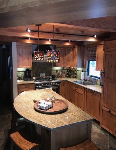 A well-lit kitchen with wooden cabinetry, granite countertops, and a central island.