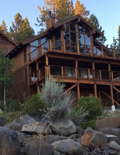 Large wooden cabin with multiple balconies nestled among trees on a rocky terrain.